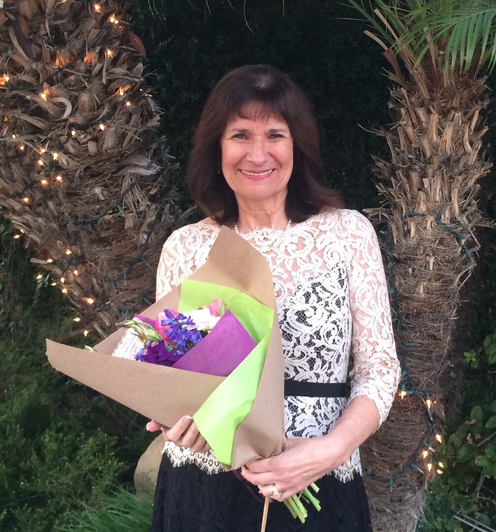 Yolanda smiling and holding a bouquet of flowers